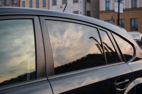 Dark car with tinted windows reflecting city buildings in Portland, OR