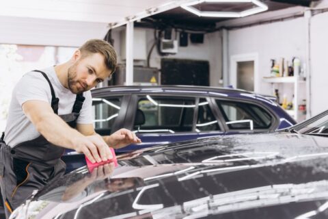 Worker smoothing protective film on car hood in Portland, OR