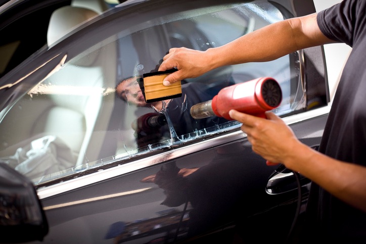 Technician using a heat gun to install car window tint in Portland, OR